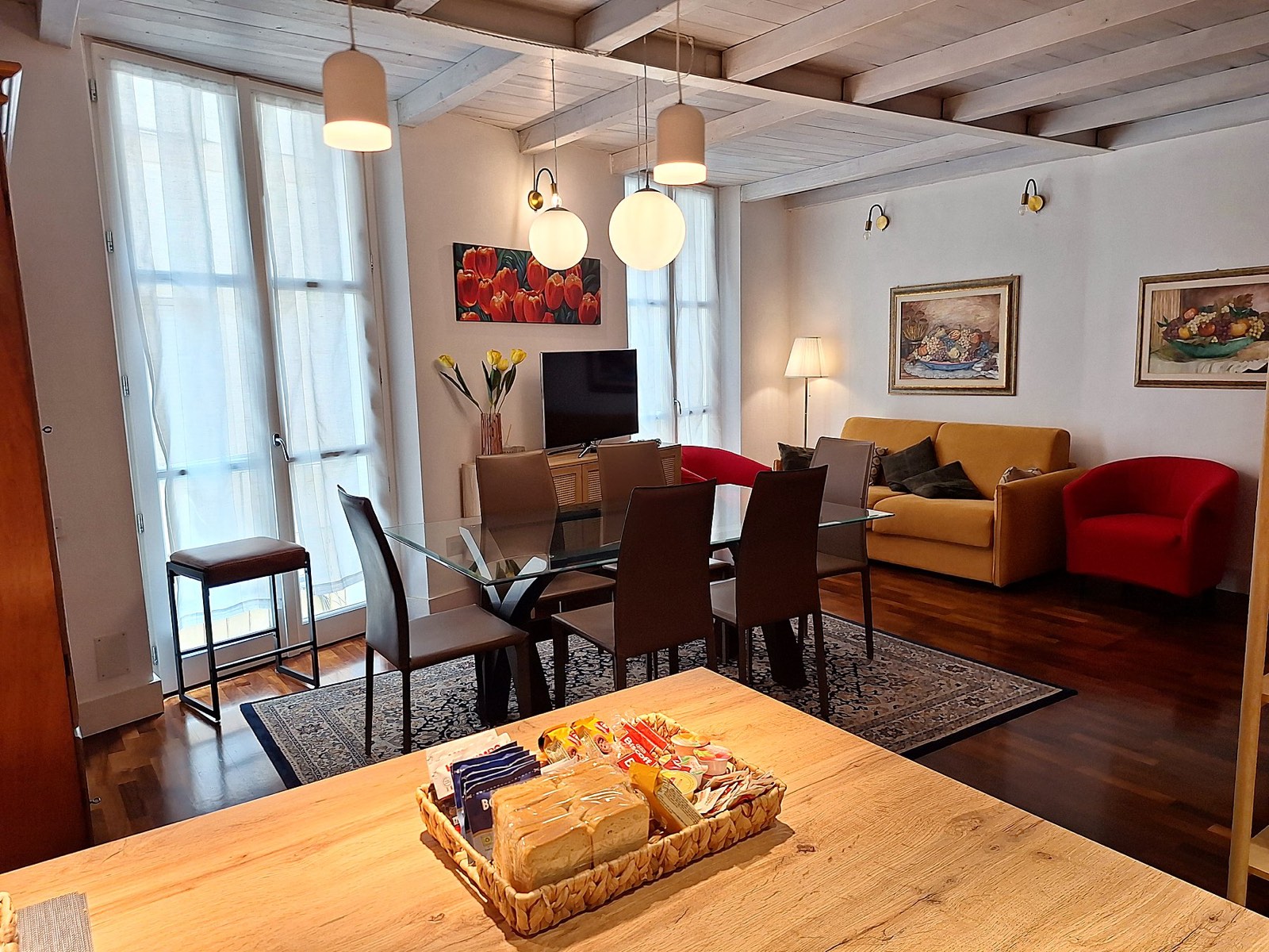 Soggiorno di Casa Lamarmora con tavolo da pranzo, divani e travi a vista
